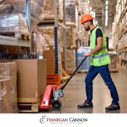 Warehouse employee in Silver Springs, MD wearing a safety vest while lifting boxes with a dolly